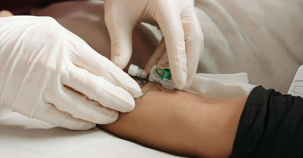 A medspa worker in gloves administers IV therapy into a customer's arm to boost immunity.