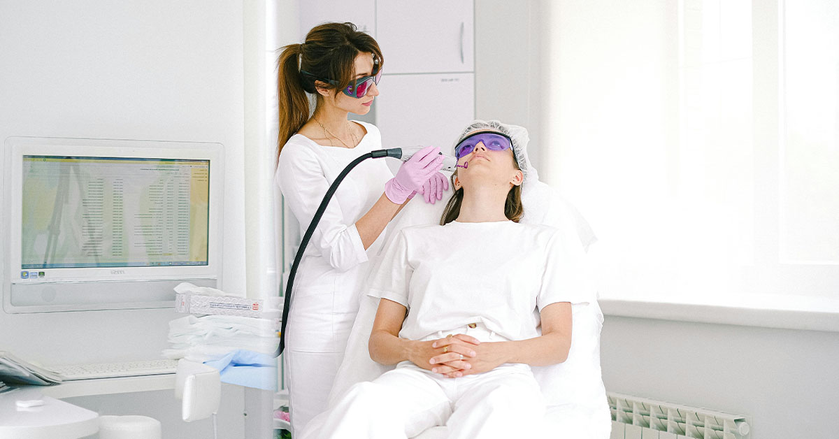 A medspa worker performs laser treatments on a patient wearing goggles in a spa clinic.